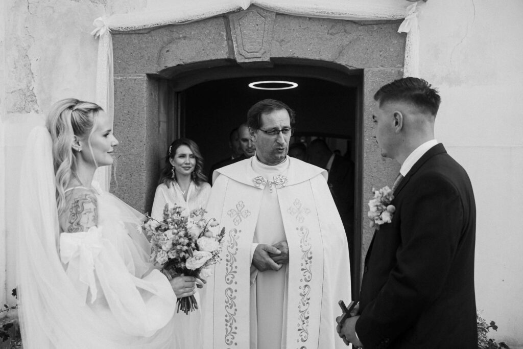 mladomanželia pri bráne kostola v Košiciach s kňazom - svadobný fotograf Jozef Vokál